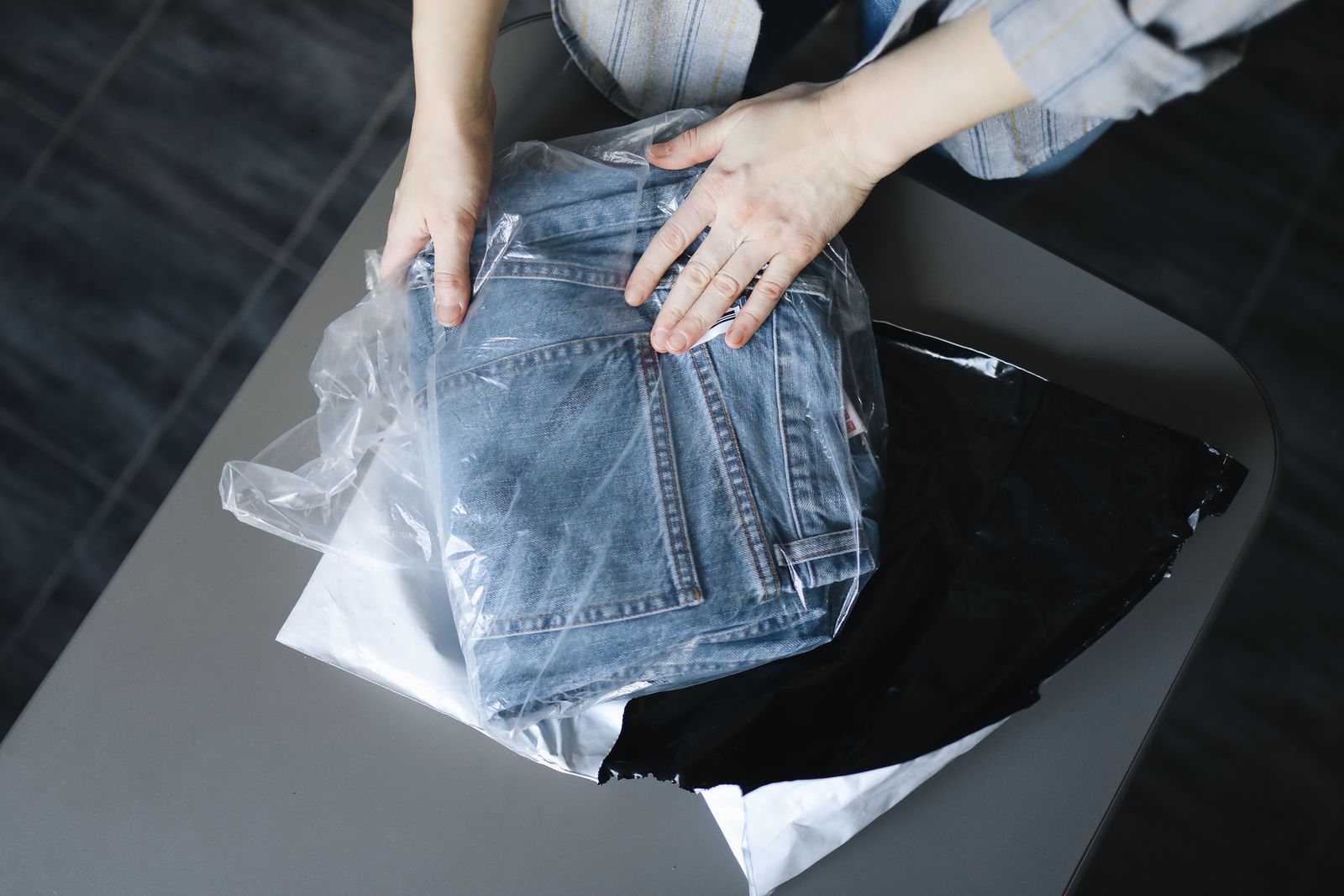 A small online seller packing a folded pair of jeans into a mailing bag
